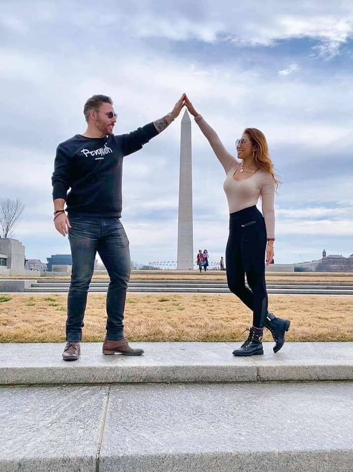 Couple poses in front of a beautiful landscape while traveling.